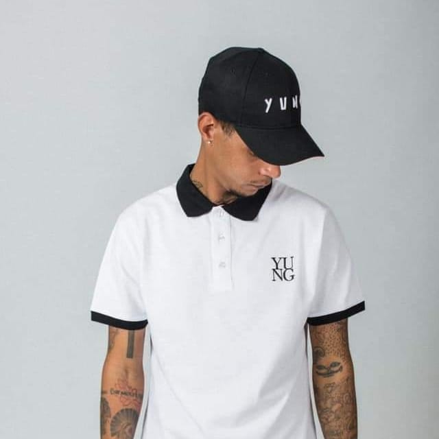 Person wearing a white golf t-shirt shirt and black cap with 'YUNG' branding on a gray background
Streetwear South Africa
