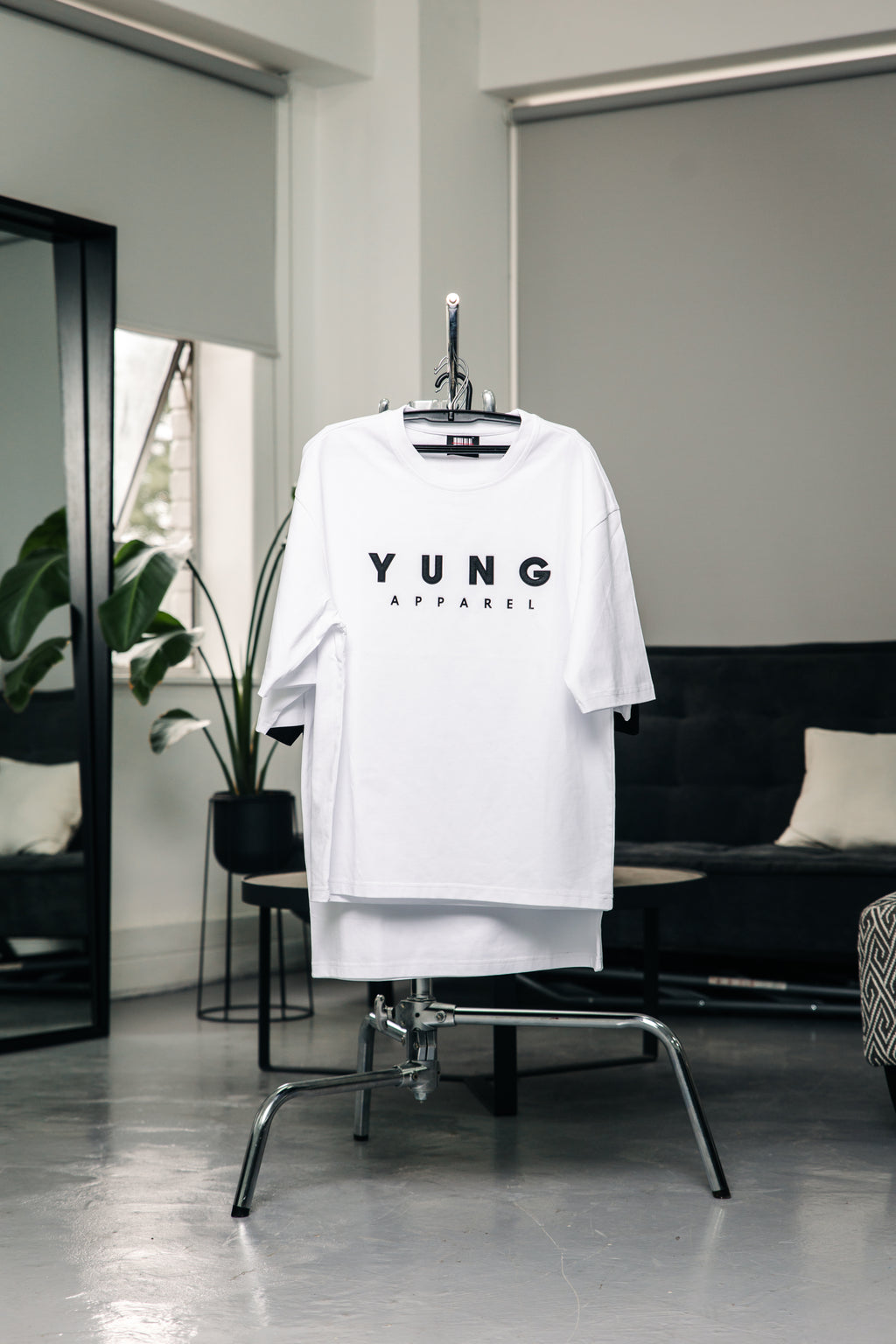 White t-shirt with 'YUNG' printed on it hanging in a modern room.
Streetwear South Africa