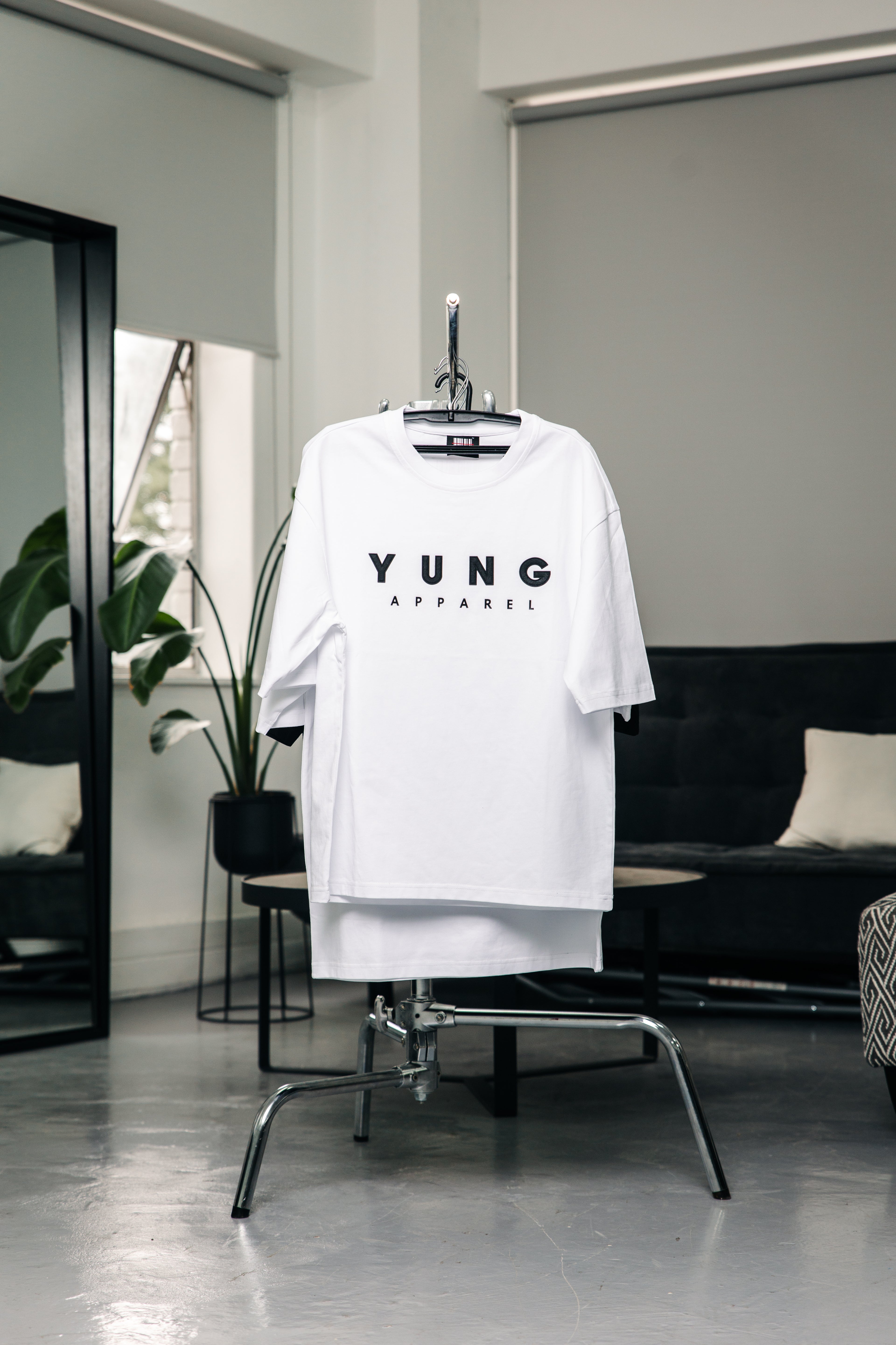 White t-shirt with 'YUNG' printed on it hanging in a modern room.
Streetwear South Africa