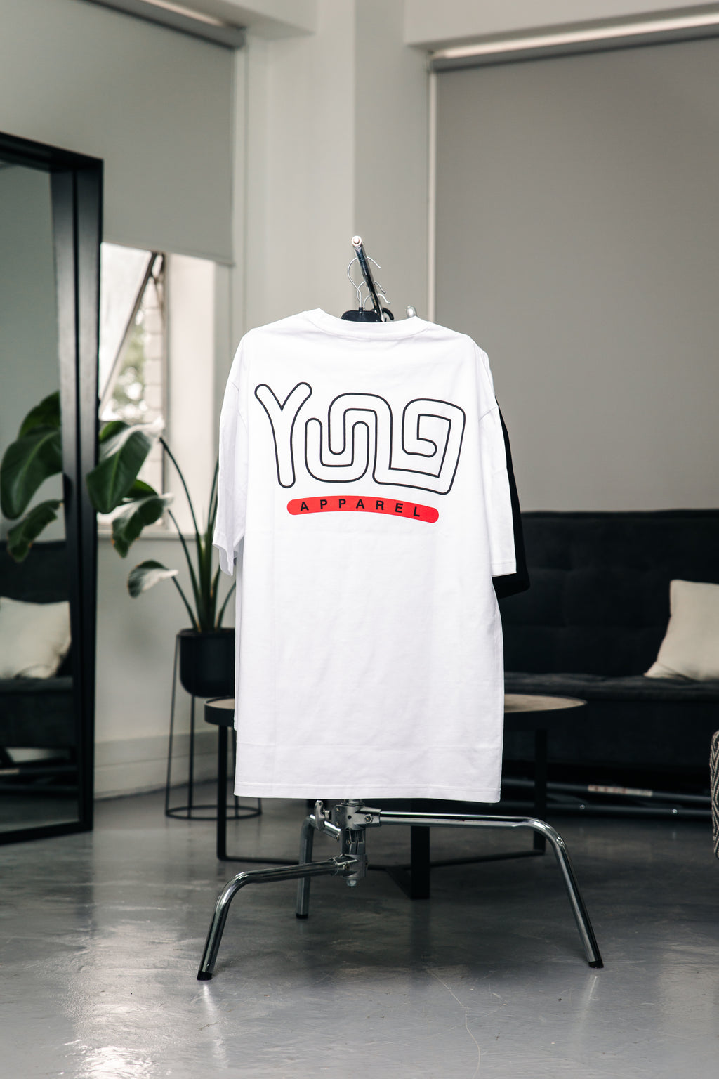 YUNG White t-shirt with black and red text on a chair in a modern room.
Streetwear South Africa