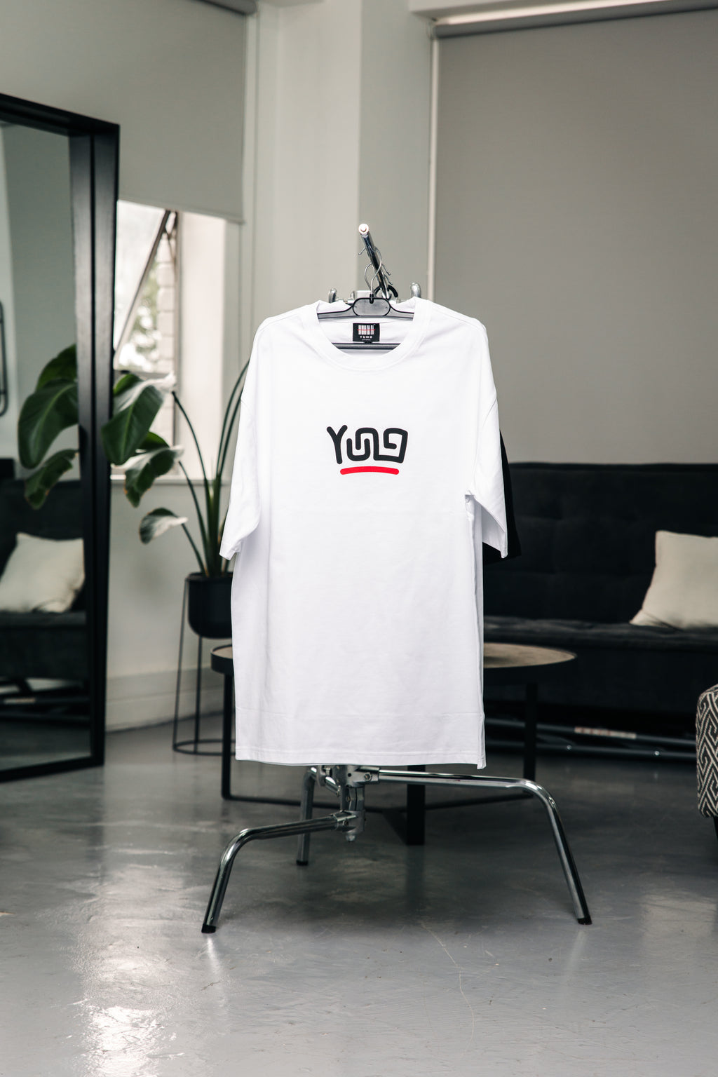 White t-shirt with black and red text on a chair in a modern room.
Streetwear South Africa