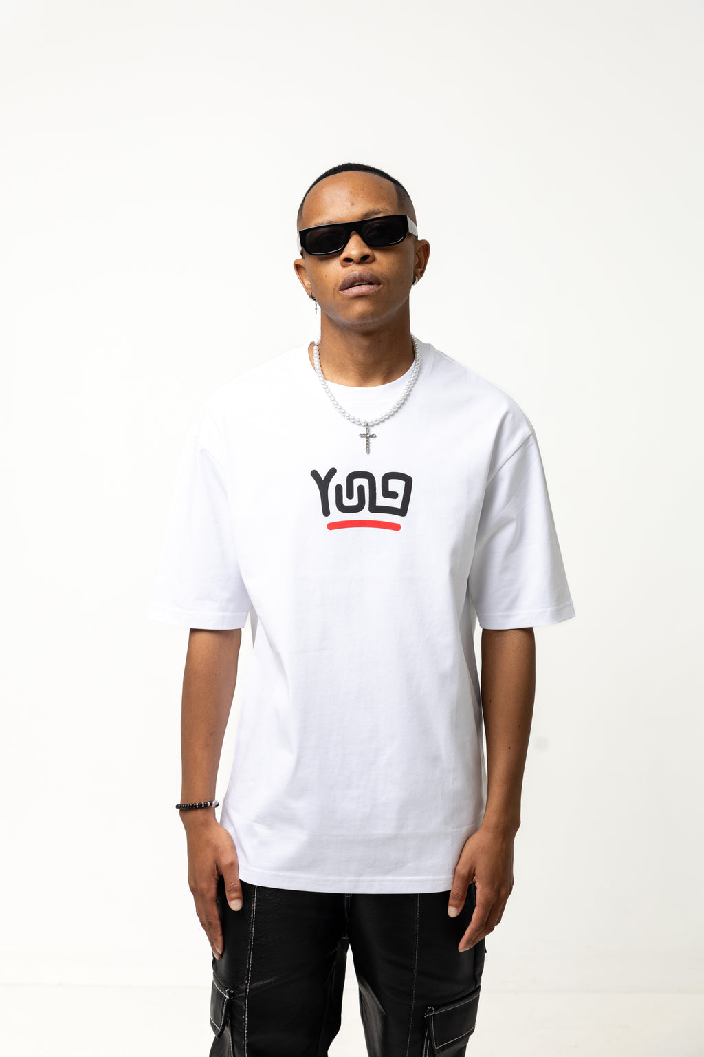 Person wearing a Y U N G white t-shirt with a logo, black pants, and sunglasses on a white background
Streetwear South Africa