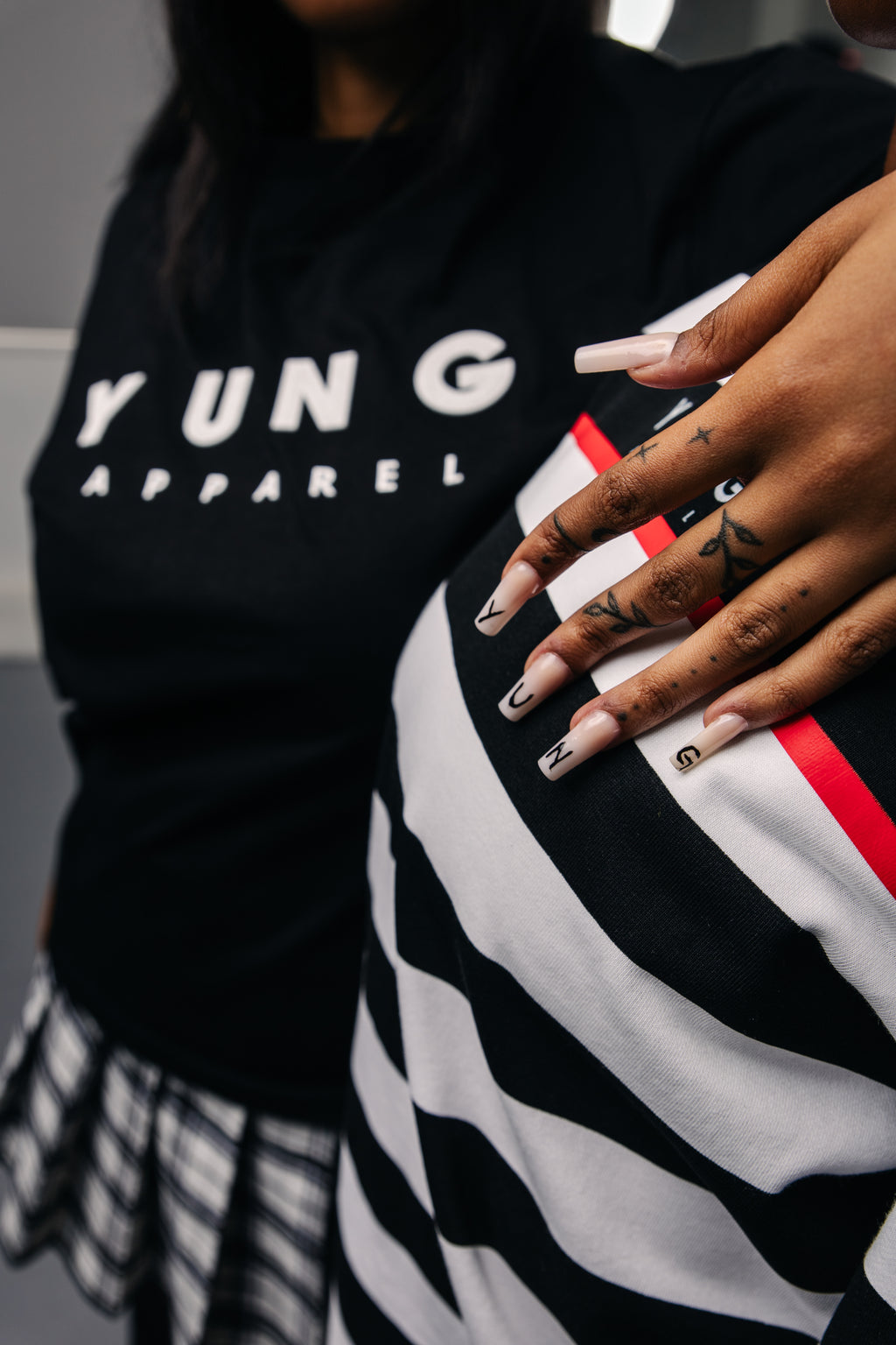 Person wearing a black hoodie with 'YUNG APPAREL' text, holding a striped garment.
Streetwear South Africa